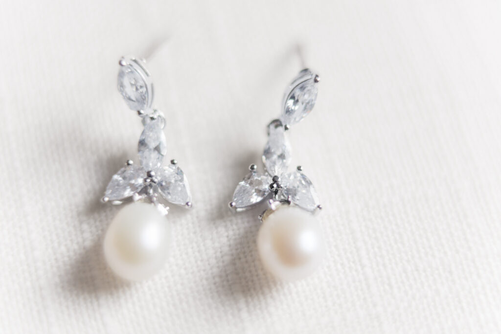 Close-up of sparkling bridal earrings resting on a lace fabric at Embassy Suites Pittsburgh Downtown.