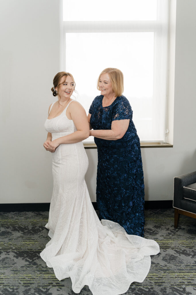 Bride’s mom helping her adjust the wedding dress in a heartfelt moment at Embassy Suites Pittsburgh Downtown.