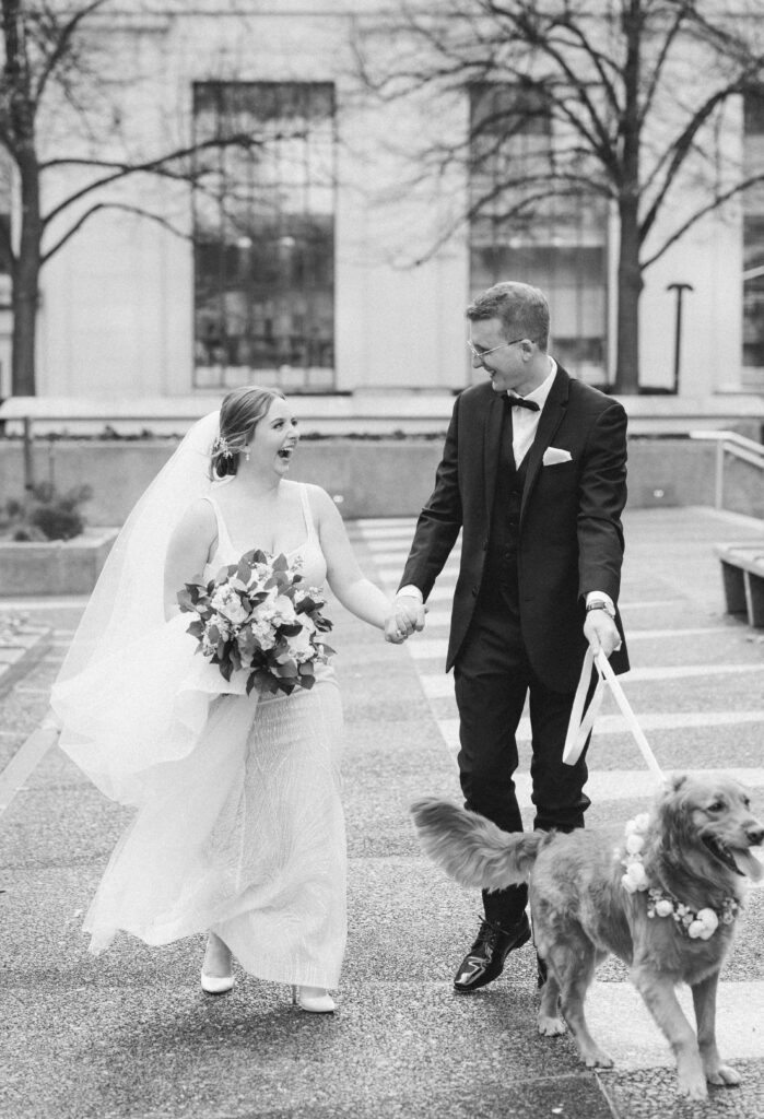 Black-and-white photo of the couple with their dogs during a heartfelt moment at Embassy Suites Pittsburgh Downtown.