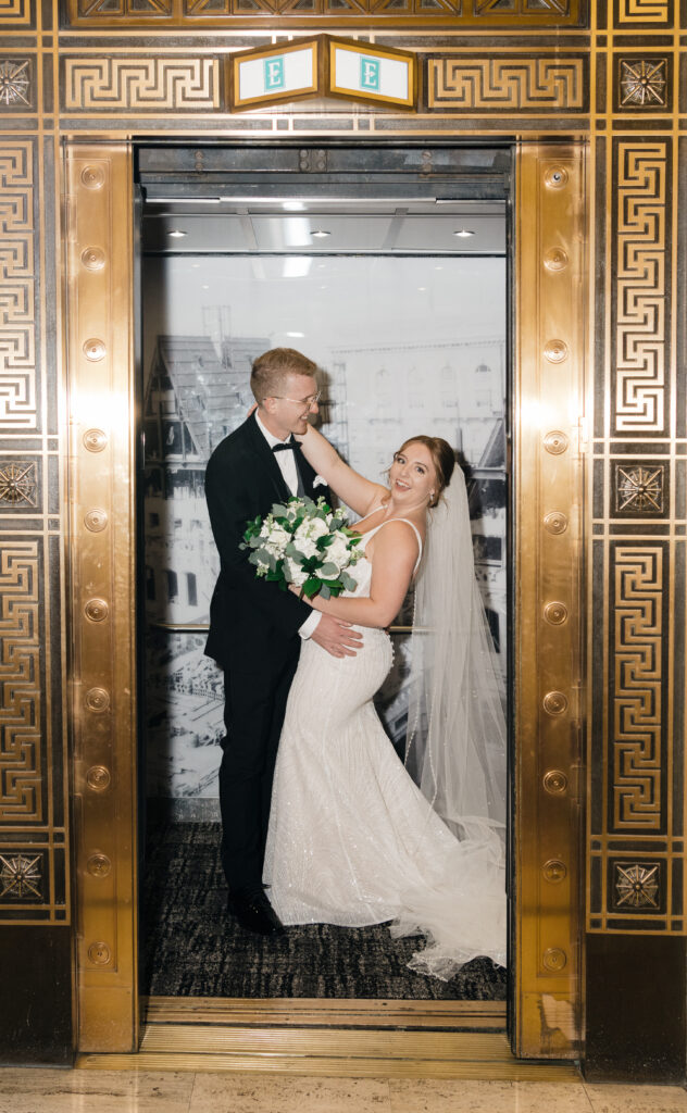 Bride and groom laughing together in an elevator at Embassy Suites Pittsburgh Downtown, captured with flash.