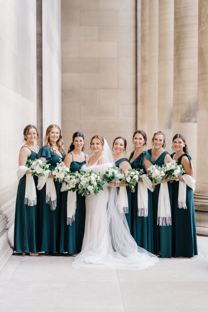 Bridesmaids laughing and holding hands in matching dresses at Embassy Suites Pittsburgh Downtown.