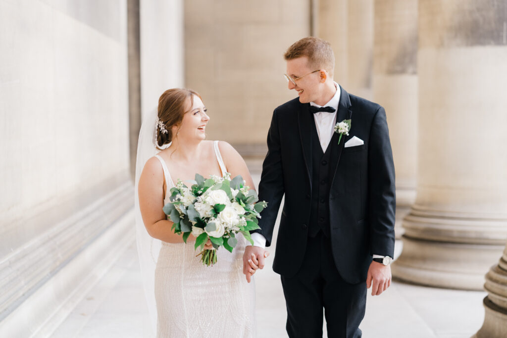 Romantic moment of the couple holding hands and gazing at each other in front of Mellon Institute Columns.