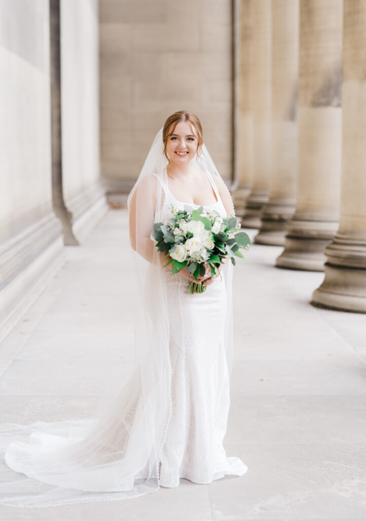 Bride posing elegantly in her wedding dress in front of the Mellon Institute Columns.