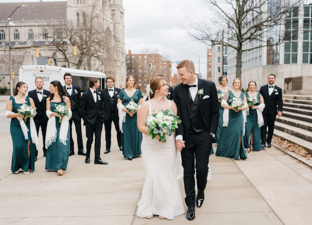 Full bridal party walking together in front of the Mellon Institute Columns, creating a joyful and stylish moment.