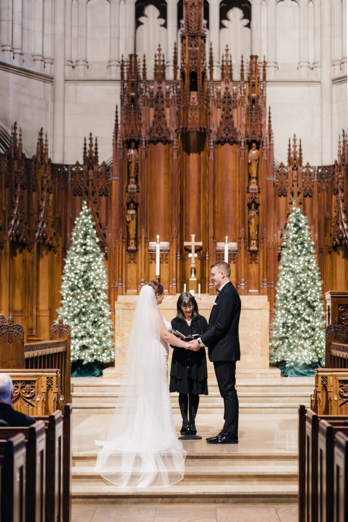 Couple holding hands as they exchange vows at the altar in Heinz Chapel.