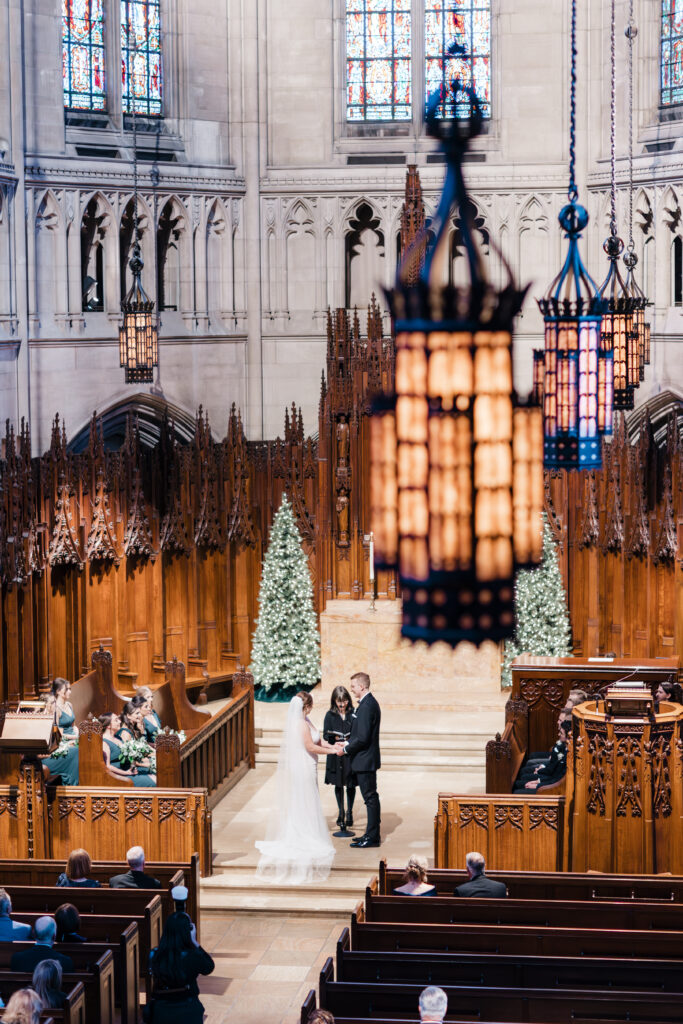 Bride and groom standing together at the altar during their wedding ceremony at Heinz Chapel.