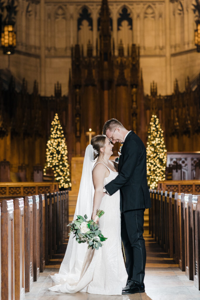 Bride and groom standing in the center of Heinz Chapel, illuminated by flash for a dramatic wedding portrait.