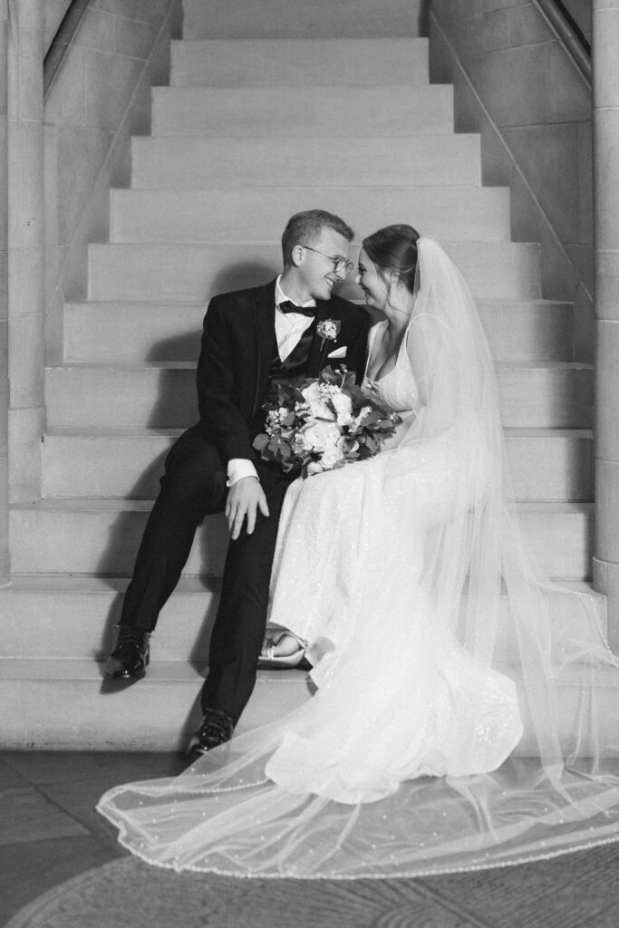 Bride and groom sitting together in Heinz Chapel, captured in a timeless black-and-white photo.