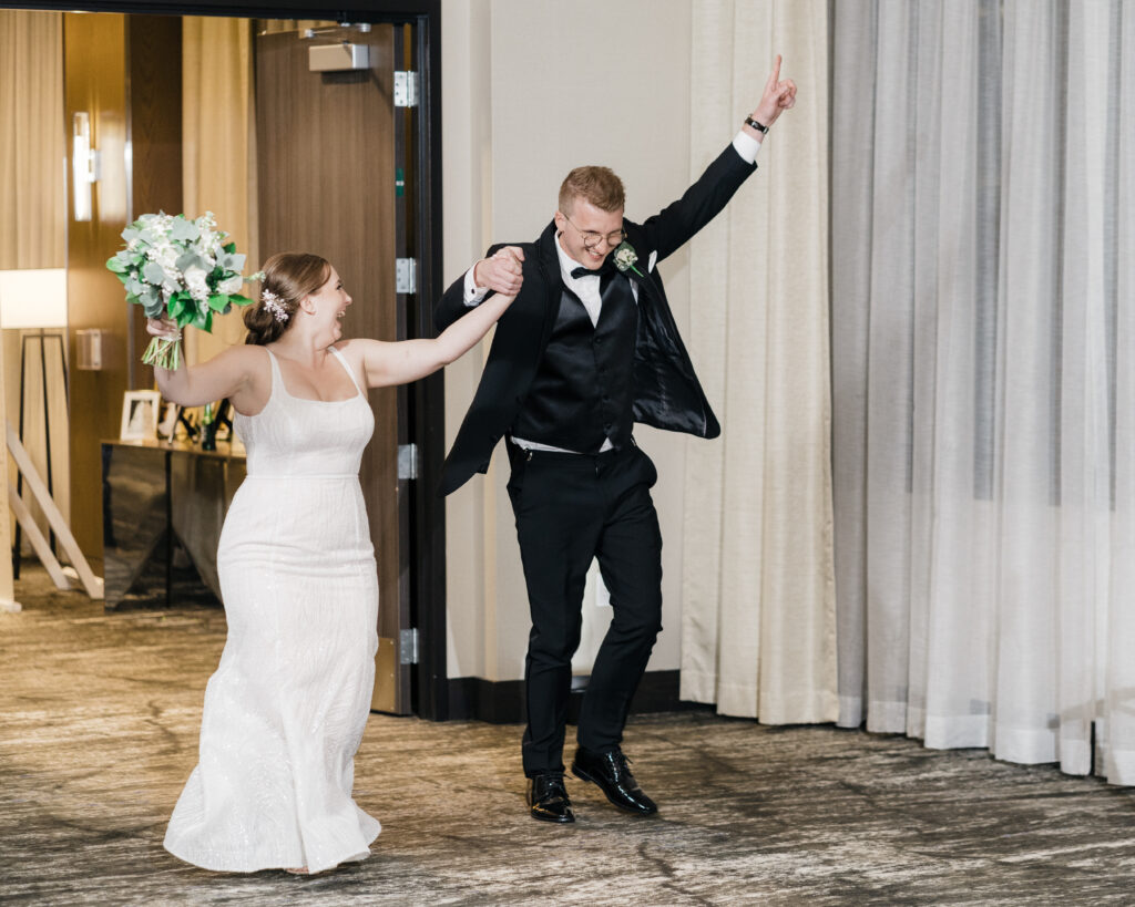 Bride and groom making a joyful entrance during their reception introductions at Embassy Suites Pittsburgh Downtown.